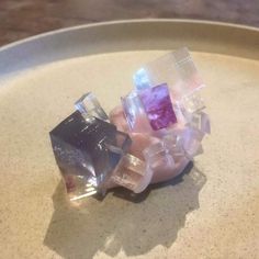 three different colored objects sitting on top of a white plate in the shape of cubes