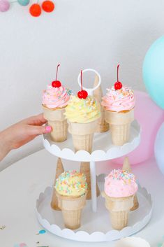 cupcakes with sprinkles and cherries are on a cake stand