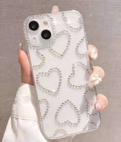 a person holding up a cell phone case with hearts and pearls on the back in their hand