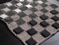 a black and white checkered blanket on a wooden table with silver squares around it