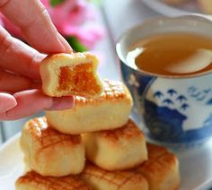 a person is picking up some food from a plate with a cup of tea in the background