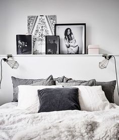 a bed with white sheets and pillows in a bedroom next to pictures on the wall