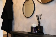 a black table topped with a vase filled with flowers and reeds next to a mirror