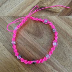 a pink bracelet with silver beads on a wooden floor