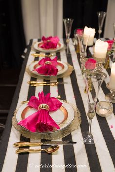 the table is set with black and white striped linens, pink napkins, silverware