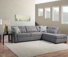 a living room with a gray sectional couch and white rugs on the hardwood floor