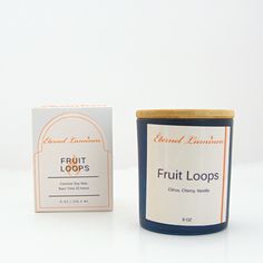 a candle next to a box of fruit loops on a white surface with an orange and blue label