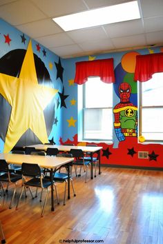 an empty classroom with wooden floors and colorful wall paintings on the walls, along with tables and chairs