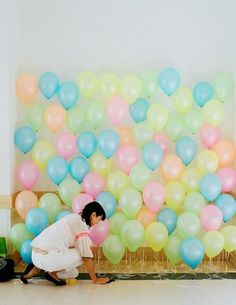 a person kneeling down in front of a bunch of balloons on a wall with the words pinterest above them