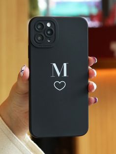 a woman holding up her phone case with the letter m on it