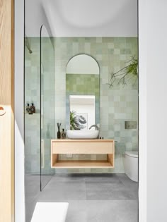 a bathroom with green and white tiles on the walls