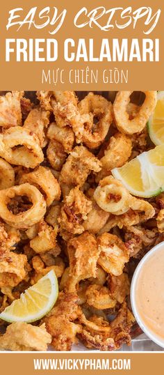 fried calamari on a plate with dipping sauce and lemon wedges next to it