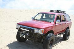 a red pick up truck parked in the sand