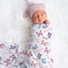 a newborn baby is sleeping on a white blanket with pink butterflies all over it's body