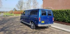 the blue van is parked on the side of the road next to a brick building