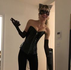 a woman dressed up as a cat in a corset and blindfold posing for the camera