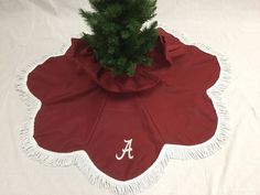 a tree skirt with the letter a on it and a small pine tree in it