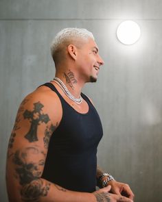 a man with white hair and tattoos standing in front of a mirror wearing a black tank top