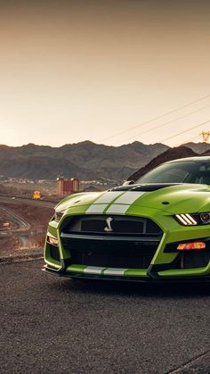 a green sports car parked on the side of the road in front of some mountains