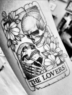 a black and white photo of a skull with flowers on it's arm that says the lovers