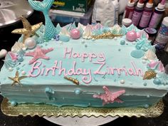 a birthday cake with blue frosting and pink decorations