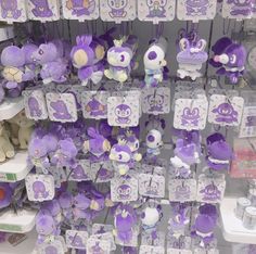 purple and white stuffed animals are on display in a toy store with tags attached to them