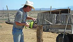 a man in a hat is working on a fence