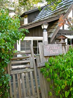 a wooden fence with a sign that says tinter bell on it next to a house