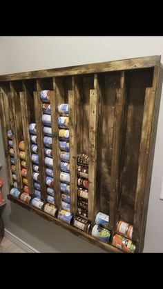 an old wooden pallet filled with canned food and cans on the wall next to a light switch