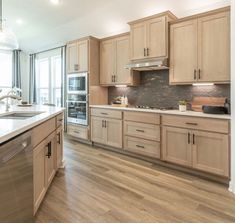 a large kitchen with wooden cabinets and stainless steel appliances, along with hardwood flooring