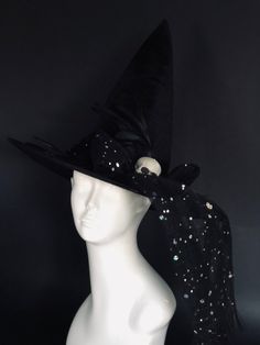 This dramatic black witch hat features sparkling dotted bow veil, feathers and a skull accent. The perfect witches hat for those who embrace the dark and mysterious side of Halloween. Age Group/Gender - Adult/Unisex Size/Type - One size fits all adults Hat Base Color - Black Hat Material - Fabric Halloween Themed Adjustable Top Hat, Themed Adjustable Top Hat For Halloween, Gothic Top Hat For Halloween Themed Events, Black Halloween Themed Top Hat, Black Witchy Wide Brim Costume Accessories, Black Fantasy Costume Accessories For Themed Events, Black Themed Top Hat For Halloween, Themed Black Top Hat For Halloween, Fitted Themed Mini Hats For Halloween