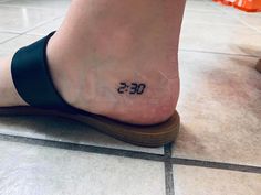 a person's foot with a small tattoo on the ankle that reads 055