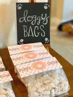 there are bags of dog treats on the table next to some chalkboard signs that say doggy bags