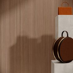 a brown and white bag sitting on top of a pedestal next to a beige wall