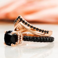 two gold rings with black and white diamonds on them, one is in the shape of a heart