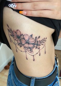 a woman's lower back tattoo with flowers on her stomach and the bottom part of her leg