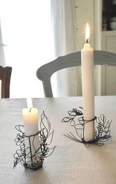 two white candles sitting on top of a table