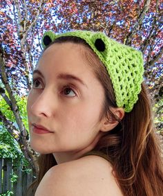 a woman wearing a green crocheted headband with a frog design on it