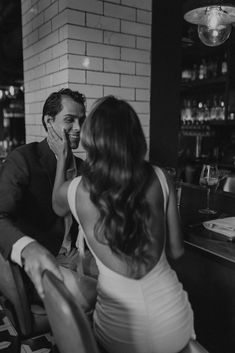 a man and woman sitting at a table in front of a bar talking to each other