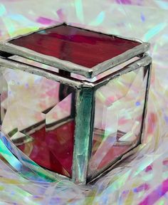 a glass object sitting on top of a colorful cloth covered tablecloth with lots of colors