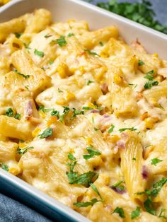 a casserole dish filled with pasta and cheese, garnished with parsley