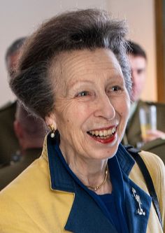 an older woman smiling at the camera with other people in the background