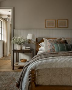 a bedroom with a bed, nightstands and pictures hanging on the wall above it