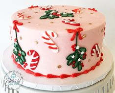 a pink cake decorated with candy canes and holly decorations on top of a white plate