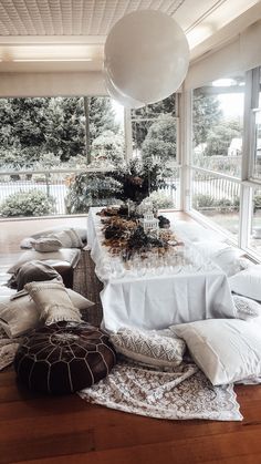 a table is set up with white linens, pillows and an air ball hanging from the ceiling