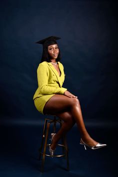 a woman sitting on top of a stool wearing a graduation hat