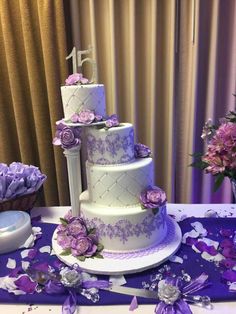 a three tiered cake with purple flowers on the table