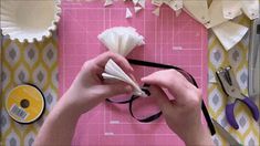 someone is cutting paper with scissors and other crafting supplies on a pink board that has been cut into smaller pieces