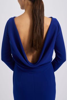 a woman in a blue dress with her back turned to the camera, wearing a ponytail