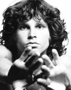 a black and white photo of a man with curly hair holding his hands out to the side